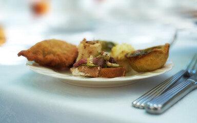 Closeup of savoury snacks served on porcelain plate and dish at a high tea event or fine dining restaurant. Texture detail of tasty pastry, pies and antipasto bread with meat for eating and tasting