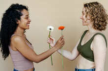 Cheerful Diverse Girlfriends Giving Flowers To Each Other