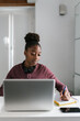 © Ezequiel Giménez/Stocksy - Black woman writing in notepad near laptop