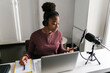 © Ezequiel Giménez/Stocksy - Serious young black female radio host using smartphone