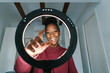 © Ezequiel Giménez/Stocksy - Happy black blogger behind ring lamp