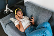 © Ezequiel Giménez/Stocksy - Young black female in headphones watching video