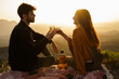© Alba Vitta/Stocksy - Cute couple having a drink making a toast on top of mountain at sunset