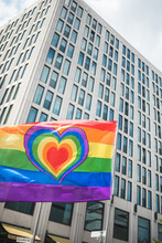 Rainbow Love Flag With A Heart Waving In Front Of The High Building