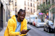© Cavan Images - young african man consulting his smartphone in the city