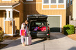 © ByLorena/Stocksy - Woman storing suitcases by car outside
