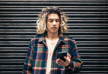 Young Man With Long Curly Hair Using Smartphone