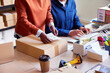 © ALTO IMAGES/Stocksy - Crop woman preparing parcel near coworker