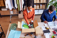 Woman Packing Parcel Near Colleague In Delivery Office