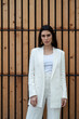 © Bisual Studio/Stocksy - Businesswoman in white suit against wooden wall