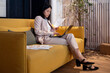 © Bisual Studio/Stocksy - Asian businesswoman working on sofa in office