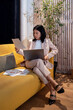 © Bisual Studio/Stocksy - Asian businesswoman working on sofa in office