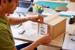 © ALTO IMAGES/Stocksy - Post office worker attaching address paper to parcel