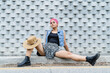 © Leonardo Borges/Stocksy - Young woman sitting on the edge of a sidewalk looking at the camera.