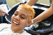 © Leonardo Borges/Stocksy - Woman in the beauty salon while having her hair washed