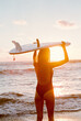 © Berena Alvarez/Stocksy - woman on black sand beach with her surfboard
