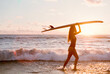 © Berena Alvarez/Stocksy - woman on black sand beach with her surfboard
