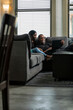 © Sean Locke/Stocksy - Loft: Couple Sits On Couch Looking At Laptop