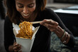 © Sean Locke/Stocksy - Loft: Woman Eating From Box Of Lo Mein
