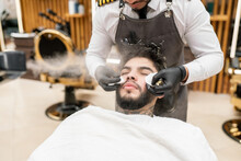 Man Lying On Chair In Barbershop While Steam Blowing