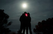 © Ibai Acevedo/Stocksy - Couple kissing with red light under the moonlight