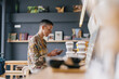 © Javier Pardina/Stocksy - Woman using phone at cafeteria bar