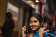 © Dream Lover/Stocksy - A young woman wearing traditional sari speaking in a smartphone