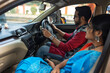© Dream Lover/Stocksy - Indian young couple sitting inside a car and browsing smartphone