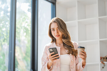 Smiling young pretty Asian business woman talking on phone in modern office workplace.