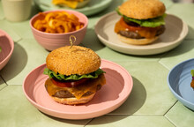 Burgers In Colorful Plates On Green Tile Background