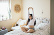 © Pedro Merino/Stocksy - Woman stretching in bed in the morning