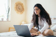 © Pedro Merino/Stocksy - Young Woman Using Laptop In The Bedroom