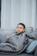 © Pattarakrich - boy wearing a blanket and watching tv