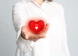 © New Africa - Woman holding red heart in hand on light grey background, closeup. Blood donation concept