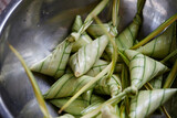 Fototapeta Kuchnia - The triangular sticky rice wrapped with palm leaf or Ketupat  Palas in a bowl