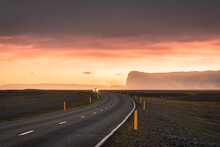 Scenic Curved Asphalt Road With Car Driving And Sunset Sky On Mountain At Iceland