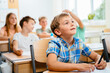© Iryna - Cute happy blond school boy sitting and listens carefully to the teacher in primary class. Smiling n child pupil studying and writing at school.