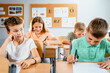 © Iryna - Bored school boy dreaming during class. Other children study sitting at the desk in classroom, writing.