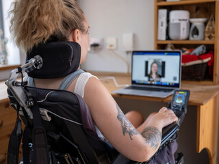 woman in electric wheelchair having video call on laptop