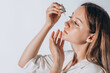 Skin care concept. Beauty portrait of young woman girl holding pipette with cosmetic oil or serum near clean face.