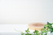 pearl white background and floor dressed with wooden plate and green ivy.