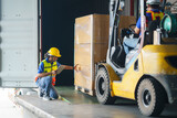 Fototapeta Paryż - Asian forklift driver loading a shipping cargo container with a full pallet with boxes in logistics port terminal. Asian warehouse worker and safety inspector with digital tablet manage the process.