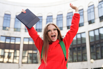 Portrait of happy excited positive cheerful teen teenager girl with tablet computer, young woman university or college student at campus outdoors smiling. Passed exam, vacation, college enrollment