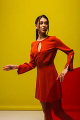 elegant young woman in red dress holding round shape glass on green.