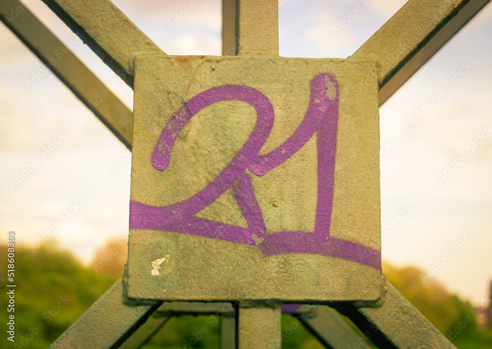 Graffiti of the number 21 on a section of an iron bridge.