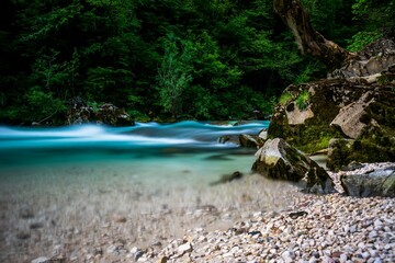 Scenic shot of a smooth river with water silky effect and rocks on the bank