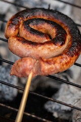 Poster - Vertical close up shot of rolled up sausages on skewer placed over barbecue