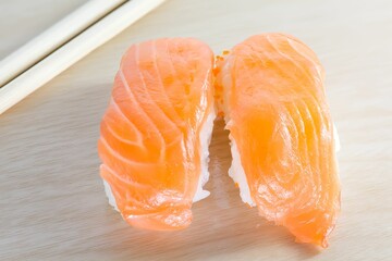 Canvas Print - Closeup shot of two salmon sushi rolls on the wooden table