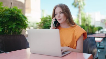 Sticker - Young woman using laptop talking on smartphone at coffee shop terrace