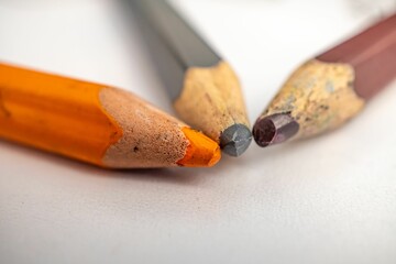 Wall Mural - Closeup of orange, black and brown pencils on a white background